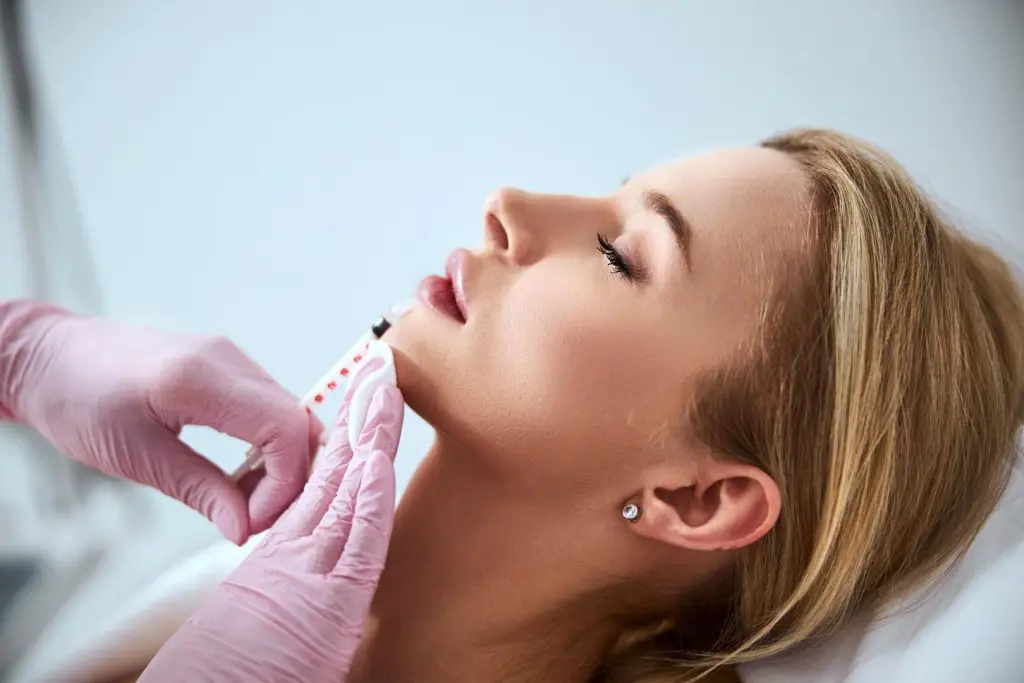 professsional cosmetologist intjecting a dermal filler into a pateints lips